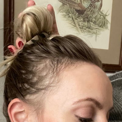 Close-up of a person with a braided hairstyle, with a decorative painting in the background.